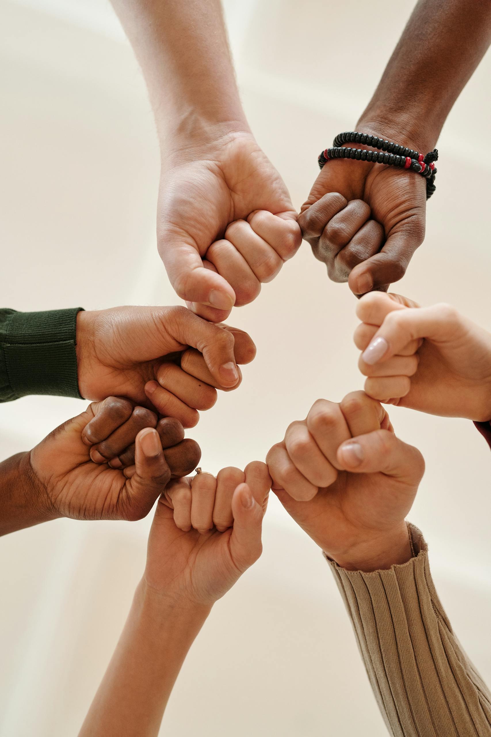Hands of diverse people fist bumping, symbolizing unity and teamwork.