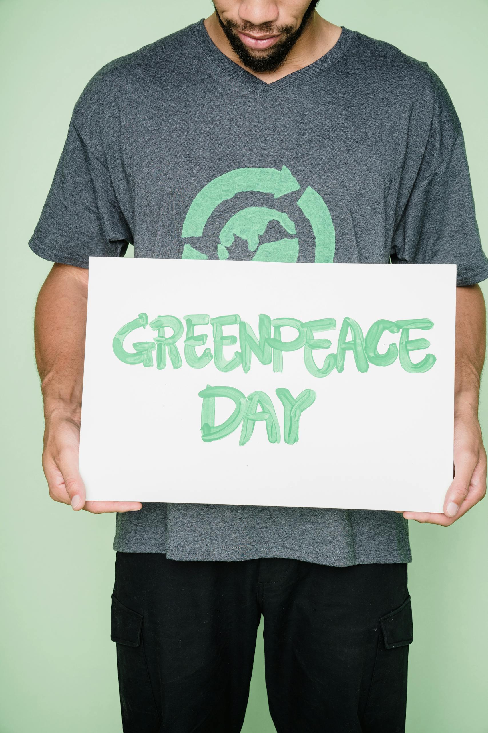 Man holding a Greenpeace Day sign, promoting environmental awareness.
